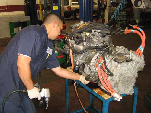 mechanic working on hybrid engine strapped to a rolling cart